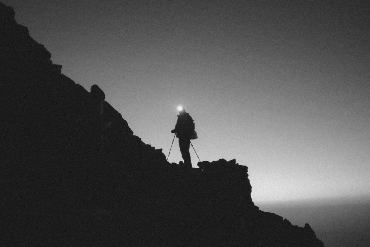 A headlamp beam cutting through darkness on a night hike